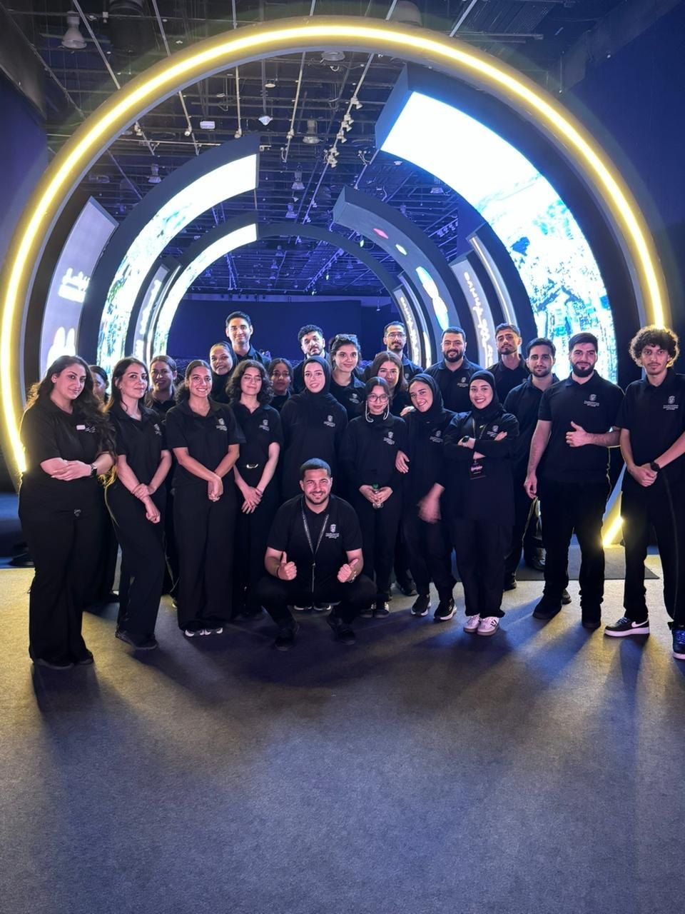 Crew in black beneath a glowing circular arch