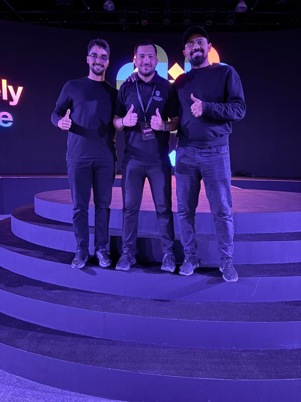 Three crew members on purple-lit stage steps