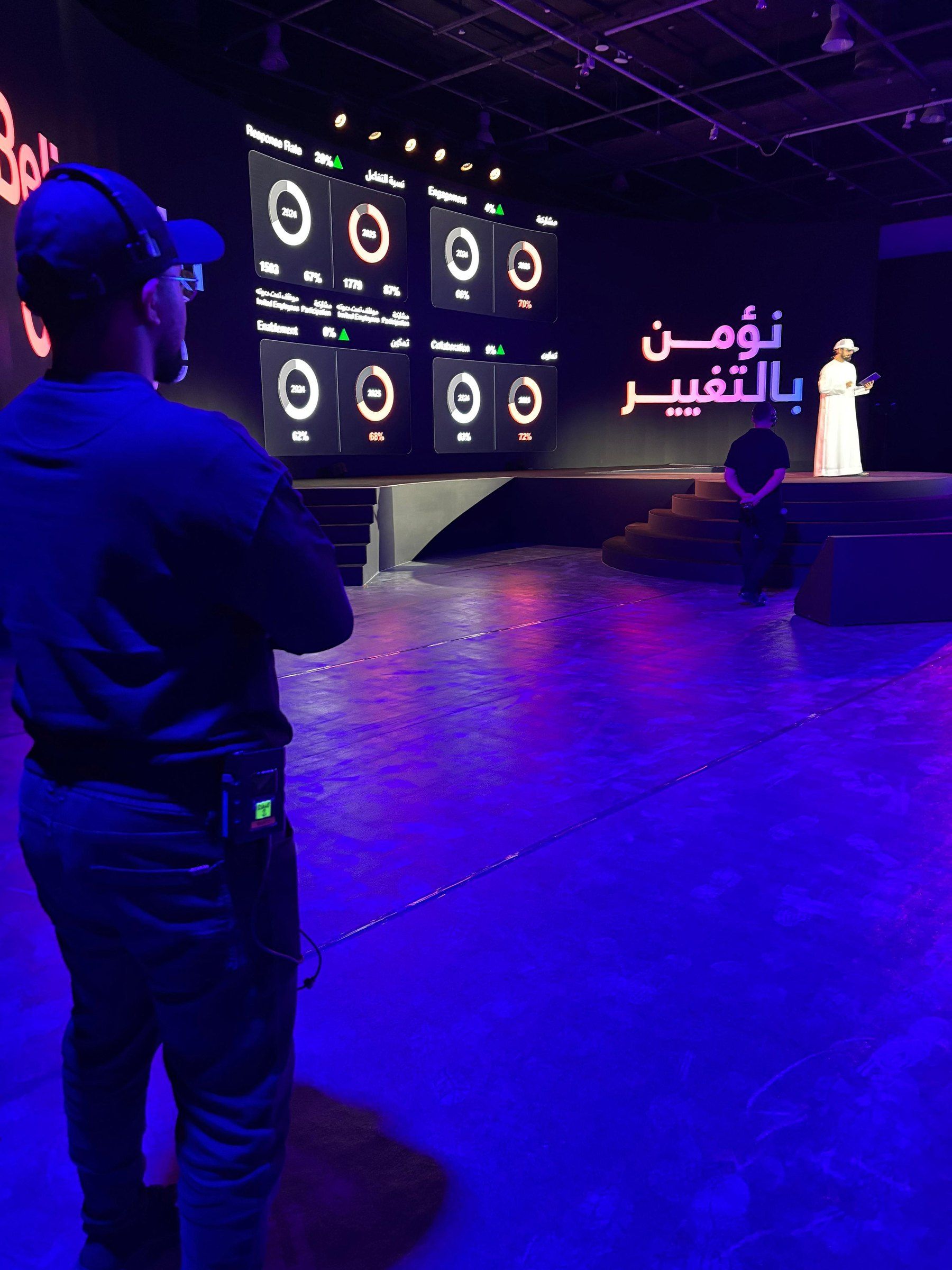 A crew member watching a stage lit in purple with data screens