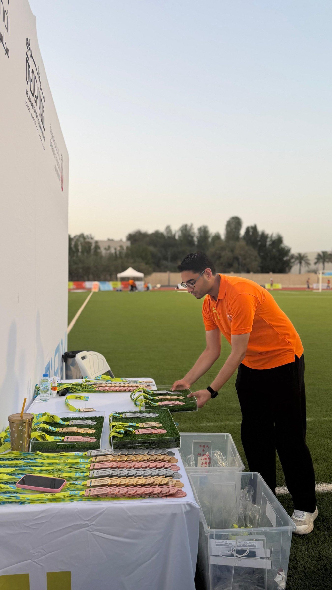 A coordinator laying out medals on a table beside the pitch