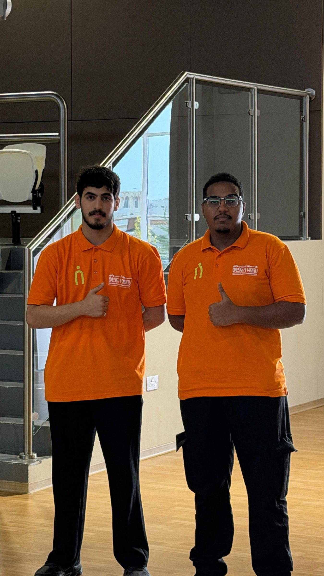 Two crew members in orange giving a thumbs up