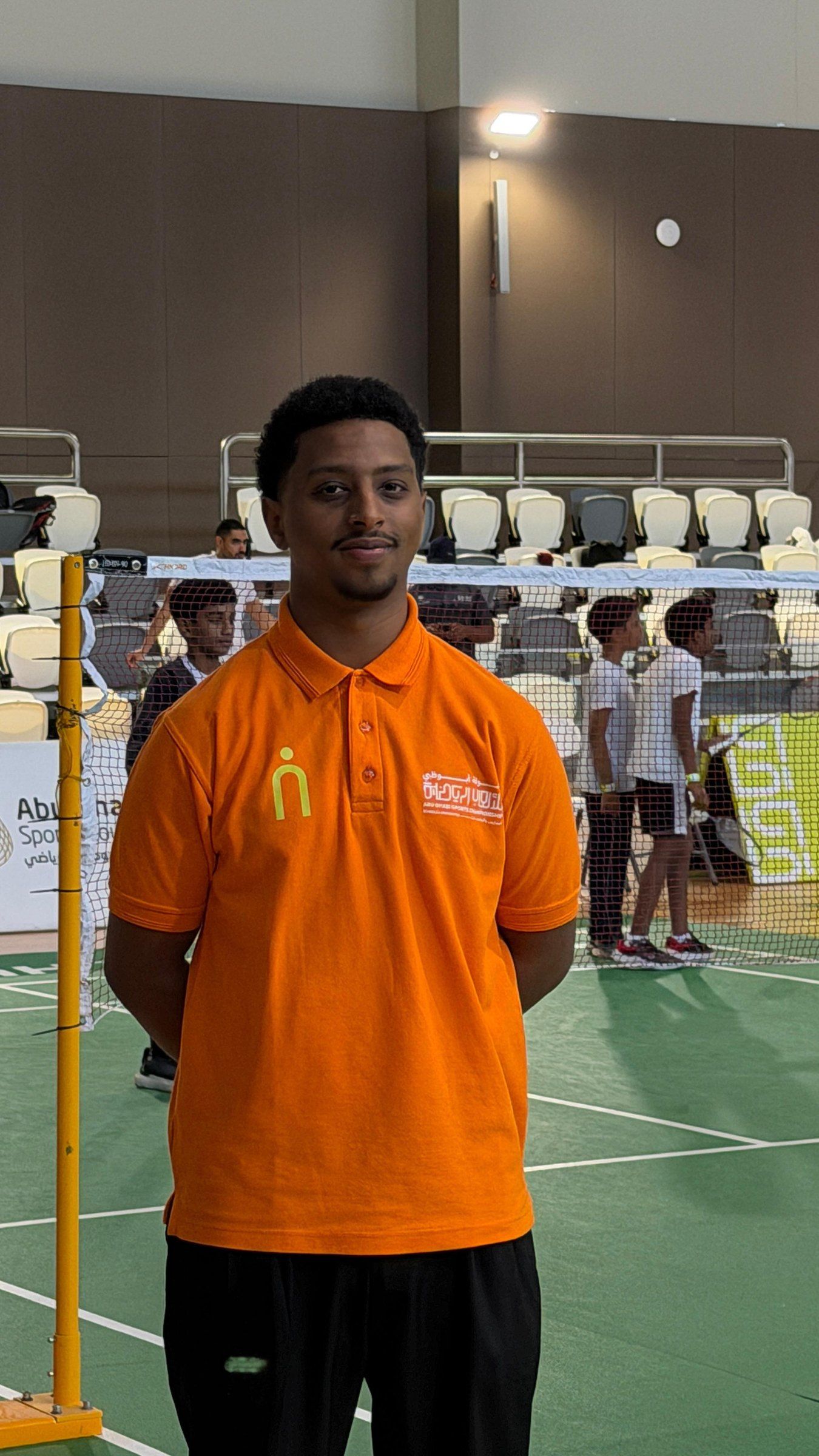 A coordinator in orange on the badminton hall floor