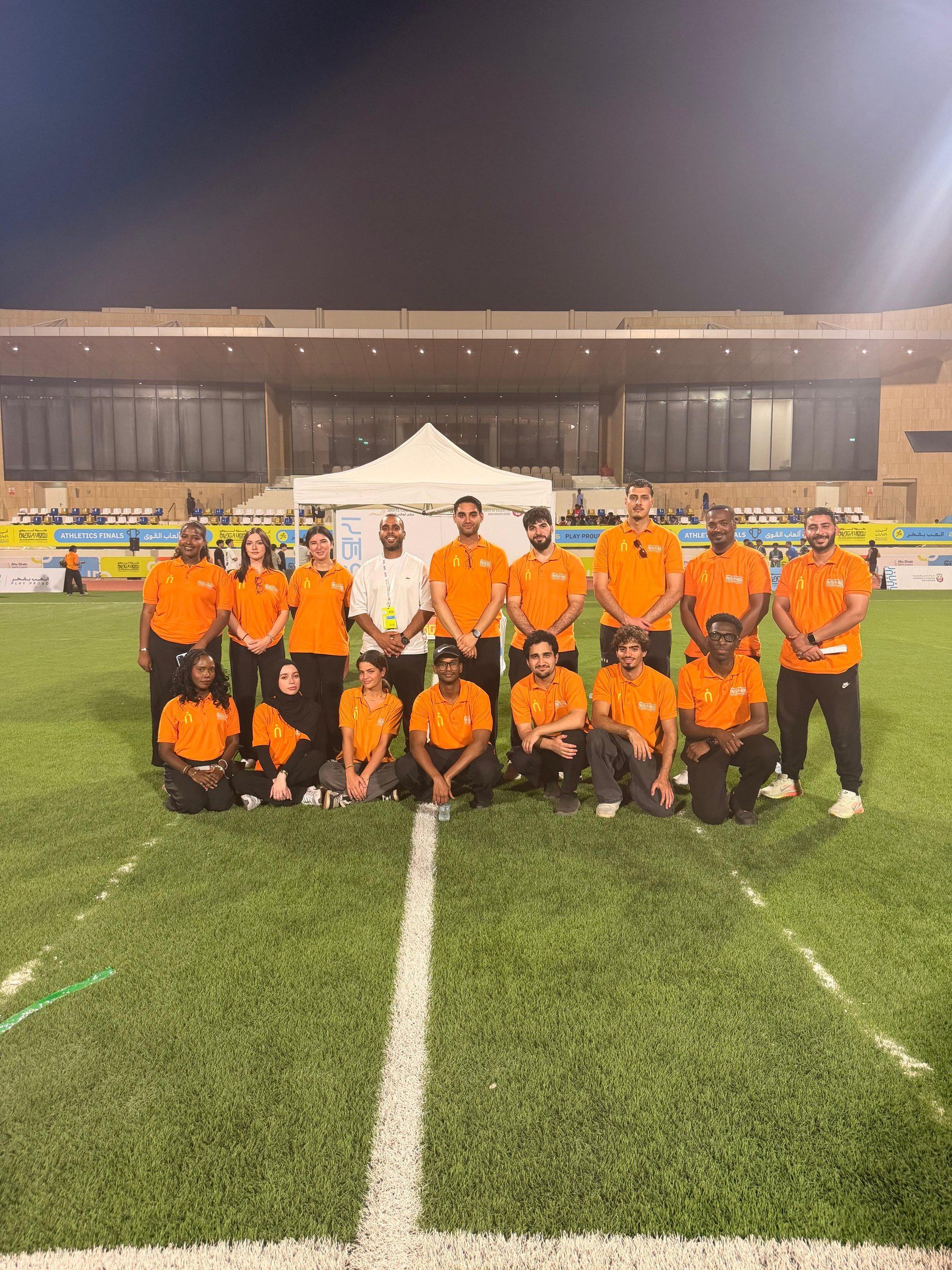 The orange-shirted team lined up on a pitch at night